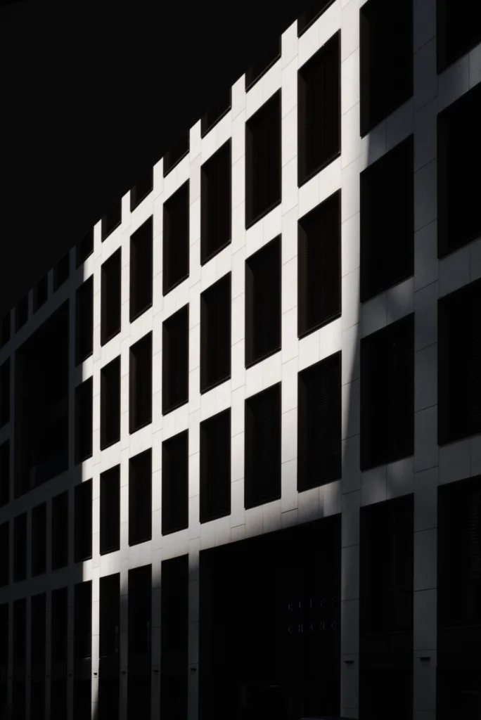 Makroaufnahme einer texturierten Hauswand oder Fassade in Schwarz-Weiß, die die Tiefe und Komplexität menschlicher Strukturen symbolisiert.