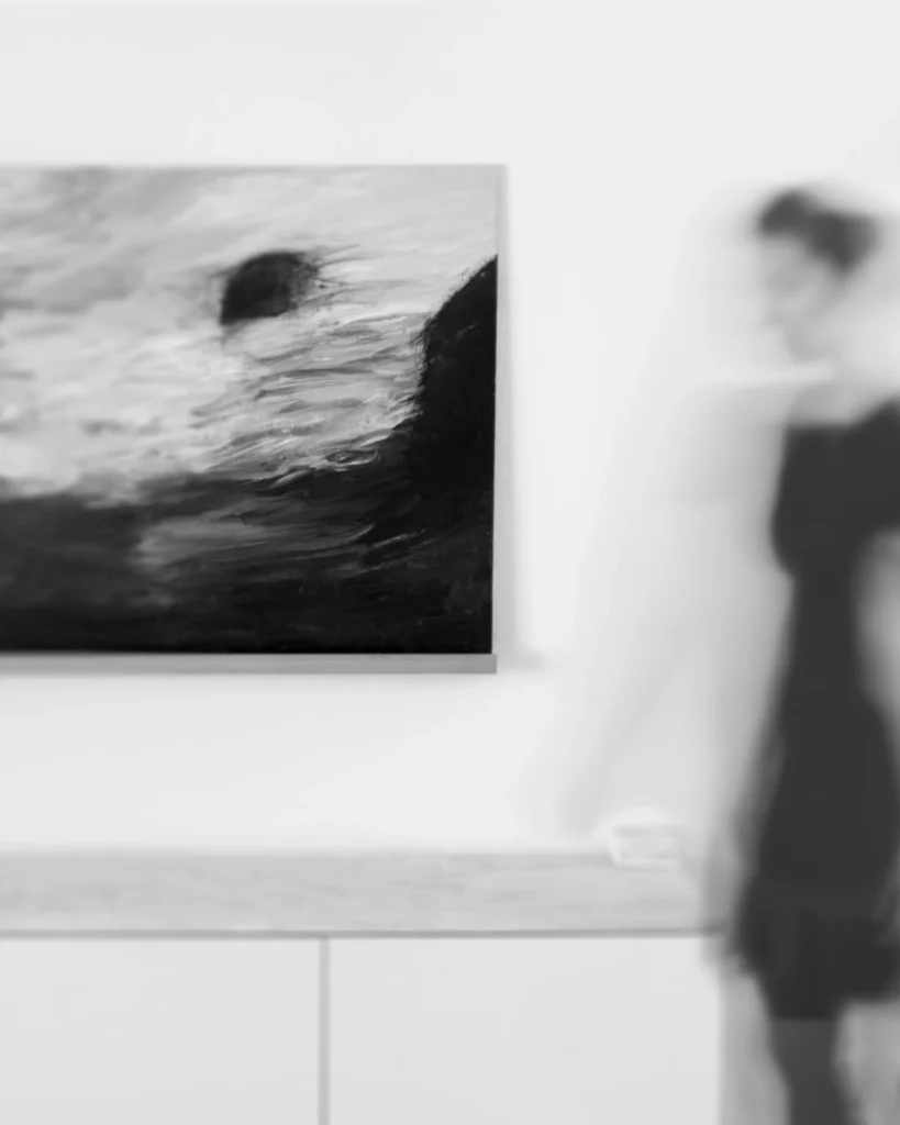Schwarz-weißes Foto einer verschwommenen, fließenden Silhouette neben einem abstrakten Gemälde, symbolisch für innere Veränderung und Bewegung im Mind & Soma Coaching.